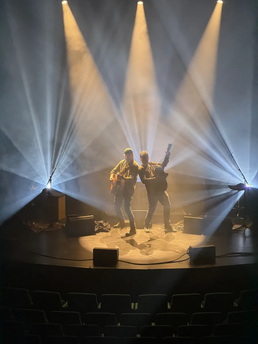 Musikere på scenen med hvide og gyldne lyskegler i haze